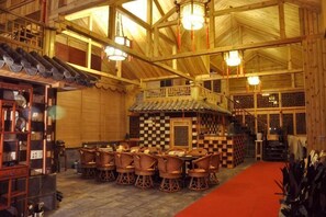 Un interior rústico de madera con un área central de comedor, una escalera y un suelo de cuadros.