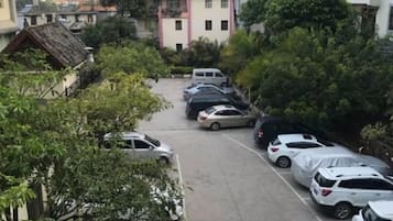 A parking lot with multiple cars parked in rows, surrounded by trees and buildings.