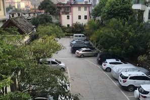 A parking lot with multiple cars parked in rows, surrounded by trees and buildings. - Chaxiang Hotel (Ning'er)