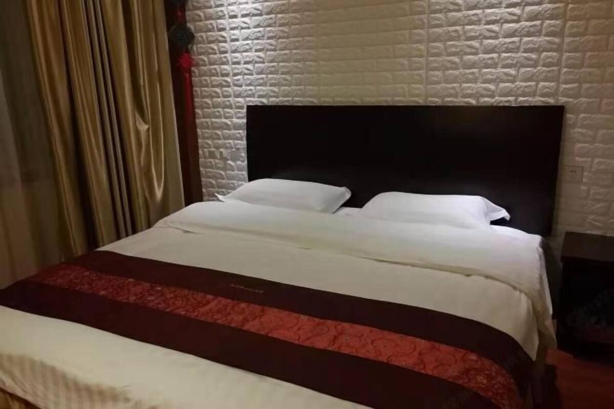 A bed with a dark headboard, white bedding, and a red and white striped blanket.