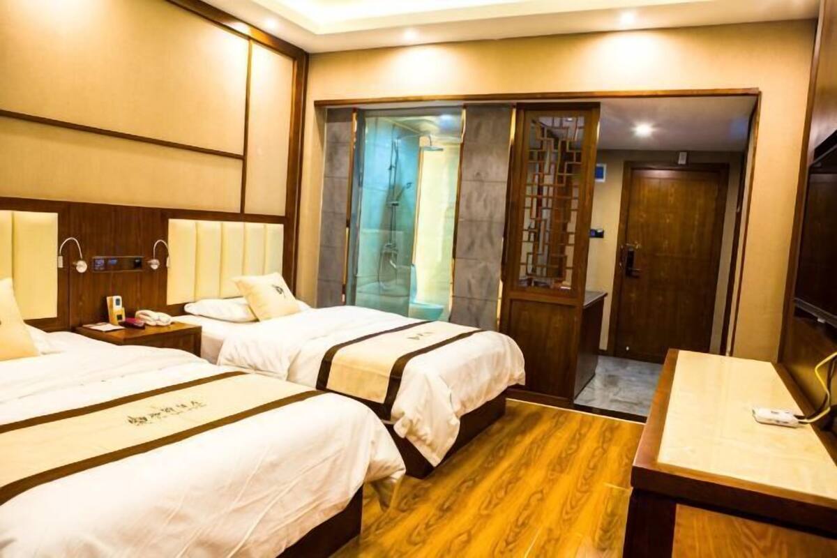 Ein Hotelzimmer mit zwei Betten, einem Schreibtisch, einem Telefon und einer Duschkabine.