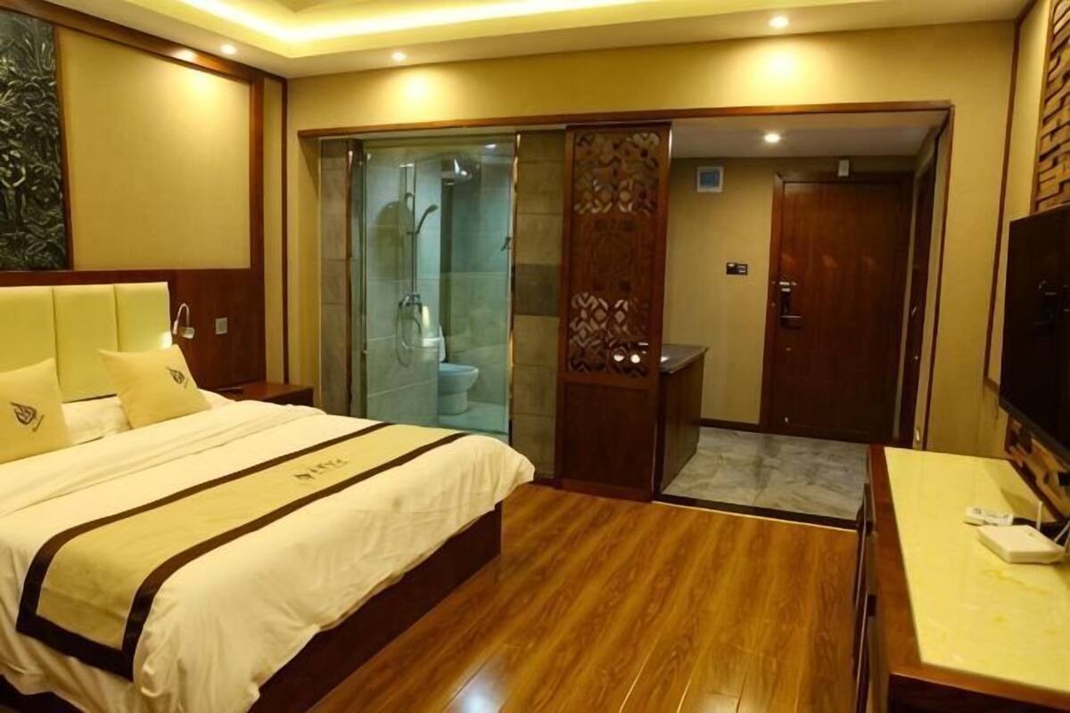 Ein Hotelzimmer mit Bett, Fernseher, Badezimmer mit Dusche und Holzboden.