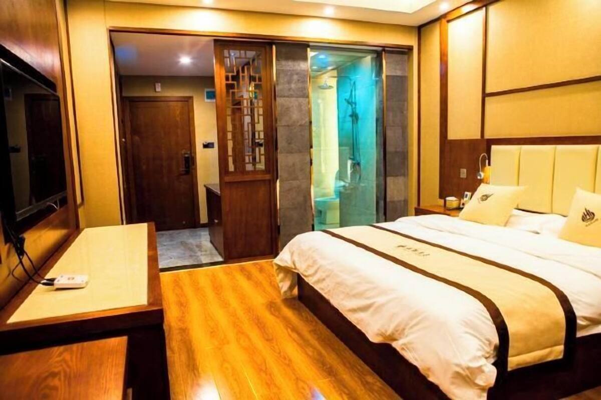 Ein Hotelzimmer mit einem Bett, einem Schreibtisch, einem Fernseher und einer Schiebetür zum Badezimmer.