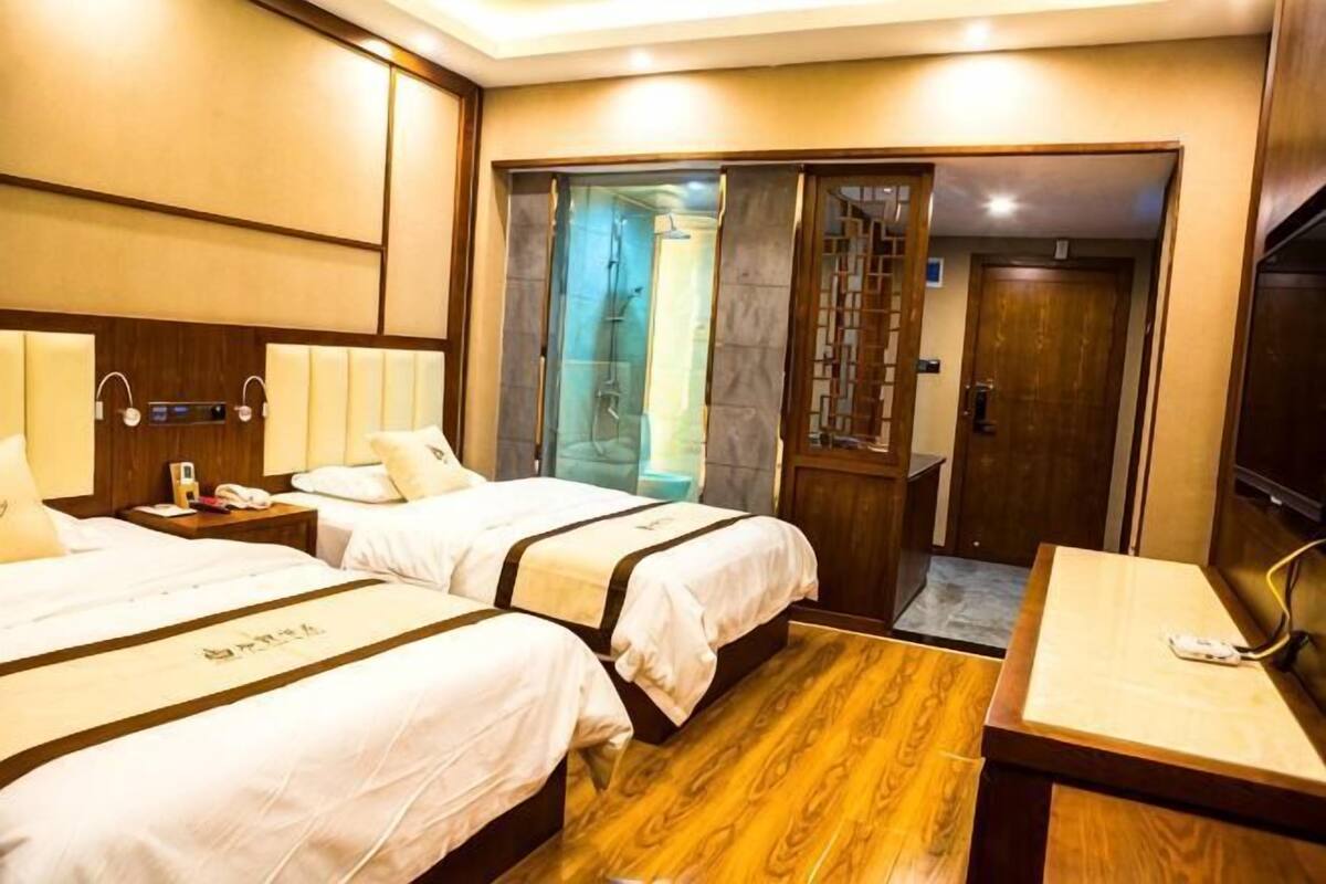 Ein Hotelzimmer mit zwei Betten, einem Schreibtisch, einer Dusche und einer Tür zu einem Badezimmer.