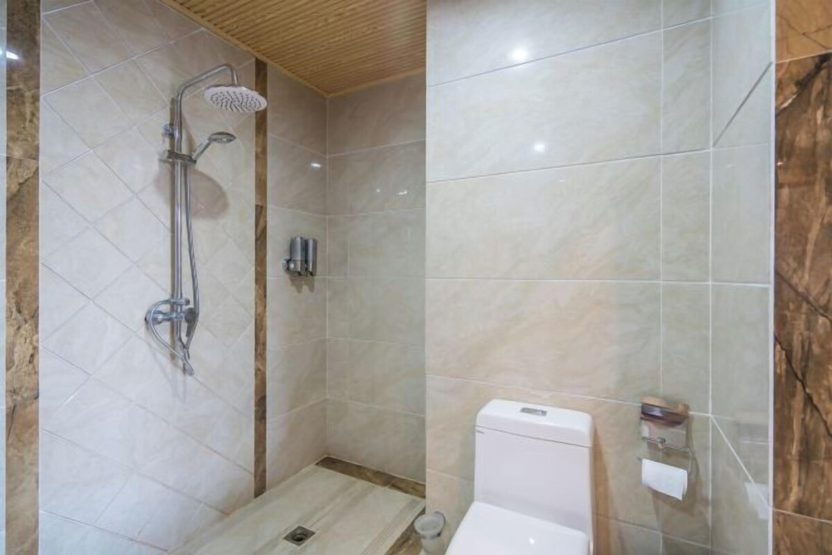 A modern bathroom with a shower, toilet, and a marble-tiled wall.