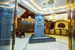 A hotel lobby with a reception desk, seating area, and a decorative pillar. - Hai Lan Hotel (Lancang)