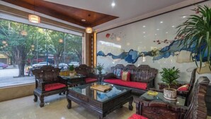 A traditional-style room with wooden furniture, a glass coffee table, and a large window offering a view of the street. - Hai Lan Hotel (Lancang)