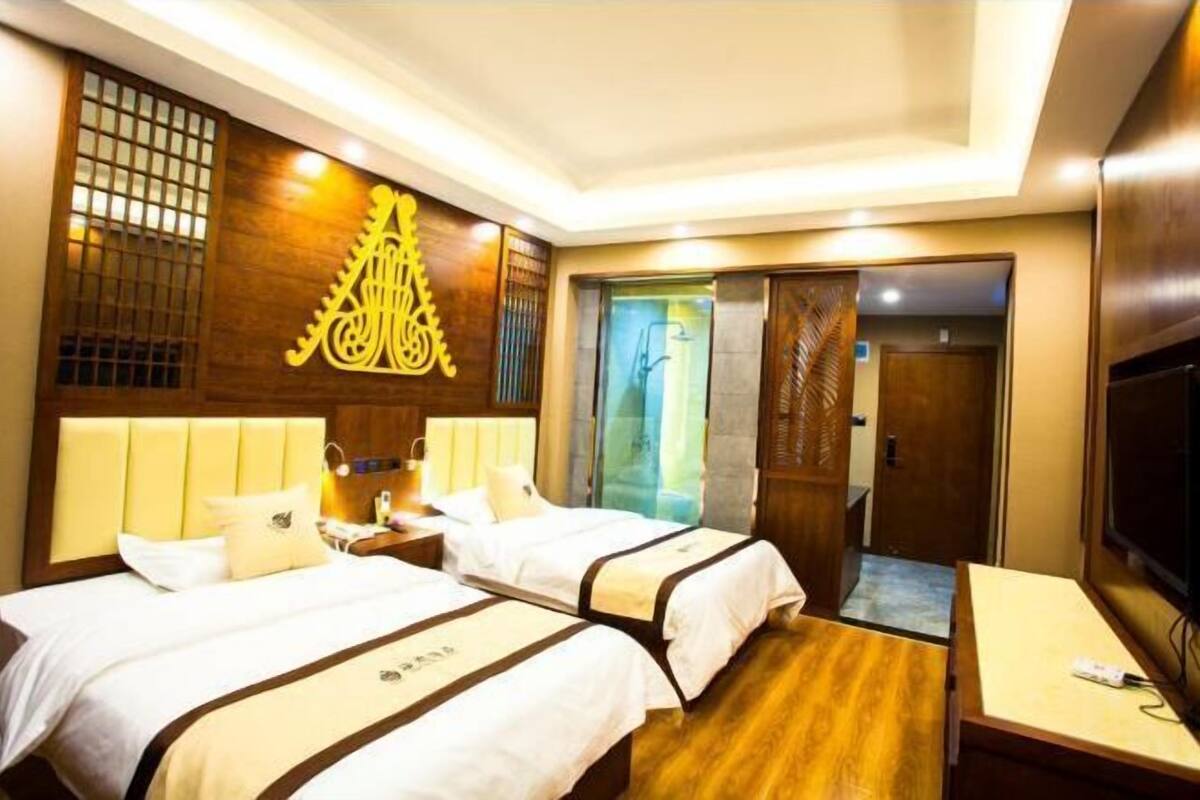 Ein Hotelzimmer mit zwei Betten, einem Fernseher, einer Wand mit Holzelementen und einer Schiebetür.