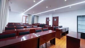 A conference room with rows of tables and chairs, a wooden floor, and a glass partition wall. - Mijng Qiyuan Minority Theme Hotel (Mojiang)