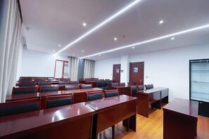 A conference room with rows of tables and chairs, a wooden floor, and a glass partition wall. - Mijng Qiyuan Minority Theme Hotel (Mojiang)