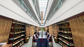 A modern interior with a central dining table, surrounded by bookshelves and seating. - Mijng Qiyuan Minority Theme Hotel (Mojiang)