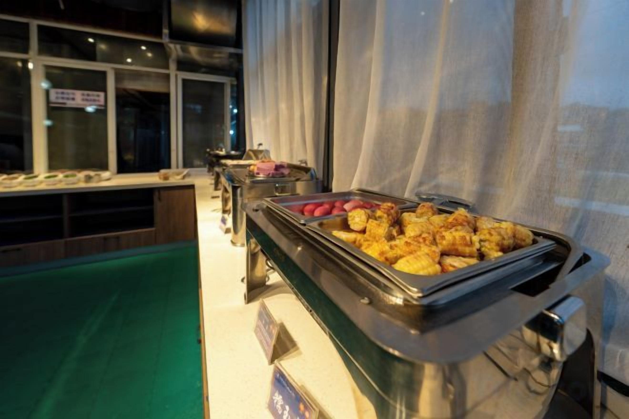 Un buffet proposant une variété de plats, dont ce qui semble être du poulet frit et des légumes.