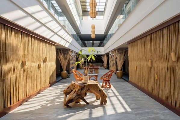 A corridor with a central seating area, bamboo walls, and a ceiling with a woven light fixture.