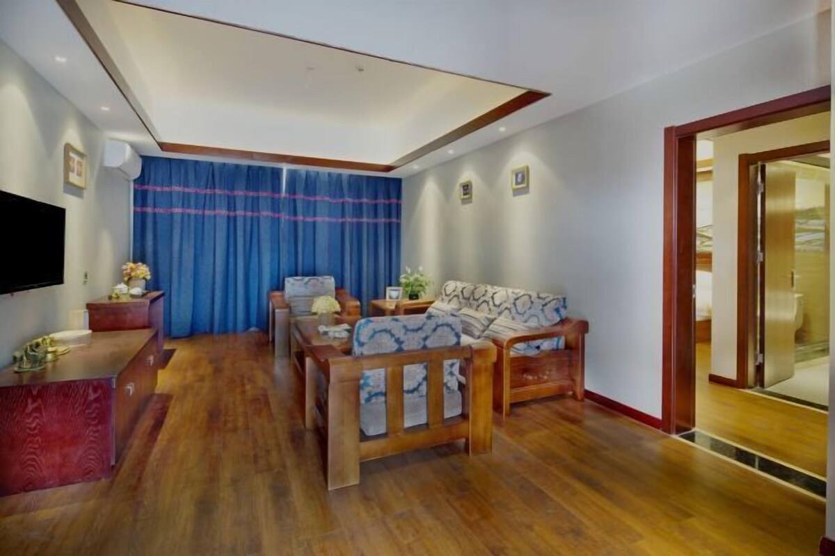 A living room with a wooden floor, a sofa, a coffee table, and a TV mounted on the wall.