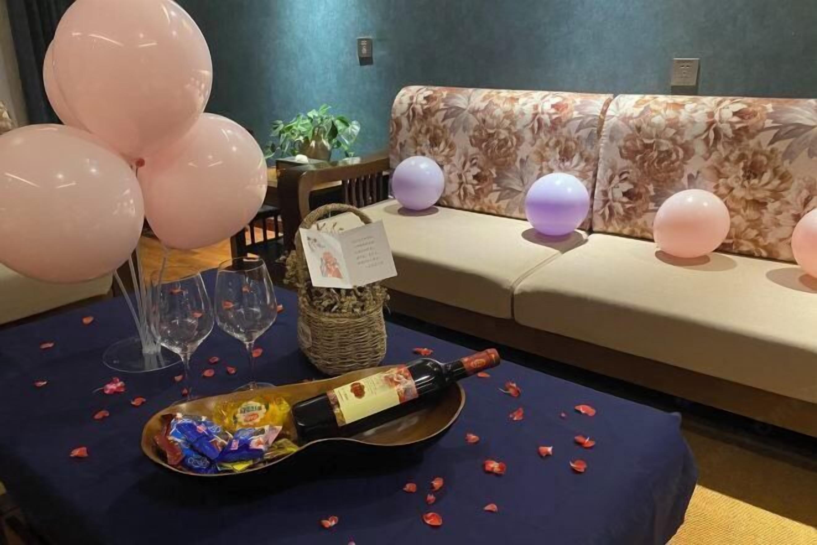 A table with a bottle of wine, glasses, and a basket of snacks.