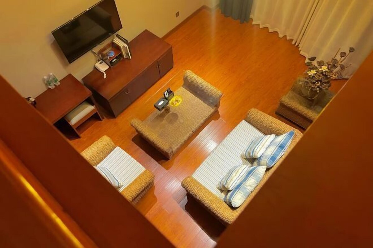 A living room with a sofa, a coffee table, a TV, and a small side table with a vase.