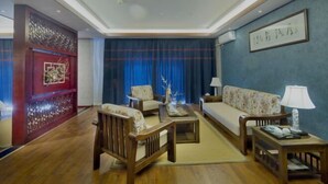 A traditional-style living room with a sofa, chairs, a coffee table, and a decorative wall piece. - Mijng Qiyuan Minority Theme Hotel (Mojiang)