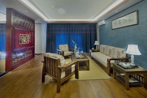 A traditional-style living room with a sofa, chairs, a coffee table, and a decorative wall piece. - Mijng Qiyuan Minority Theme Hotel (Mojiang)