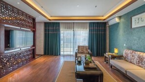 A modern living room with a flat-screen TV, a sofa, a coffee table, and a decorative screen. - Mijng Qiyuan Minority Theme Hotel (Mojiang)