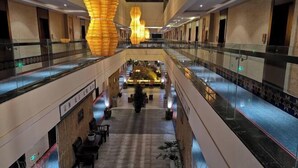 A spacious atrium with a central water feature, glass railings, and modern lighting fixtures. - Mijng Qiyuan Minority Theme Hotel (Mojiang)