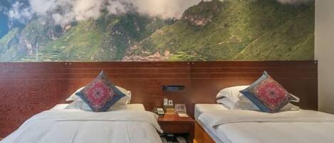 A hotel room with two beds, a nightstand, and a wall mural of a mountain landscape.