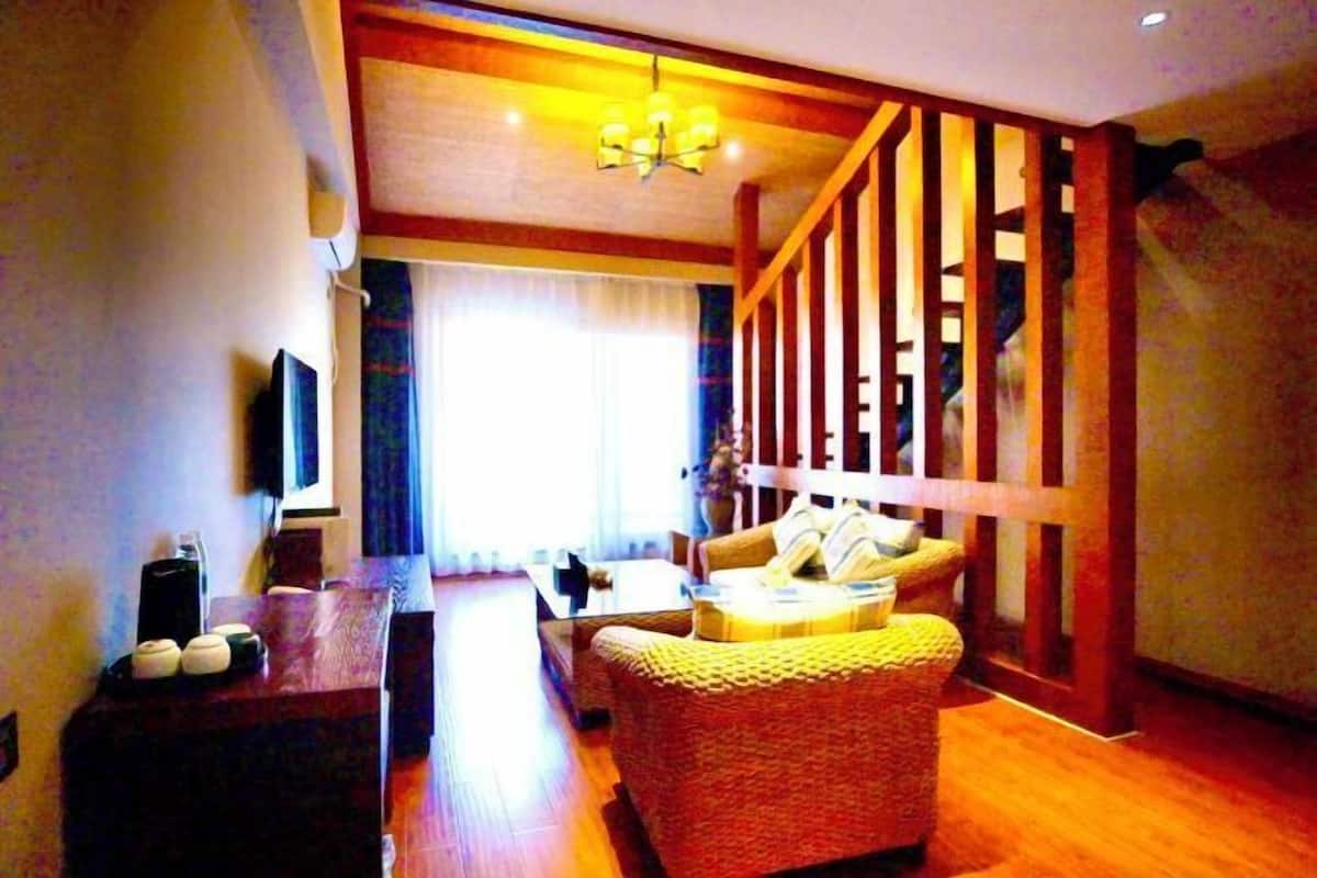 A living room with a sofa, a coffee table, a TV, and a wooden staircase.