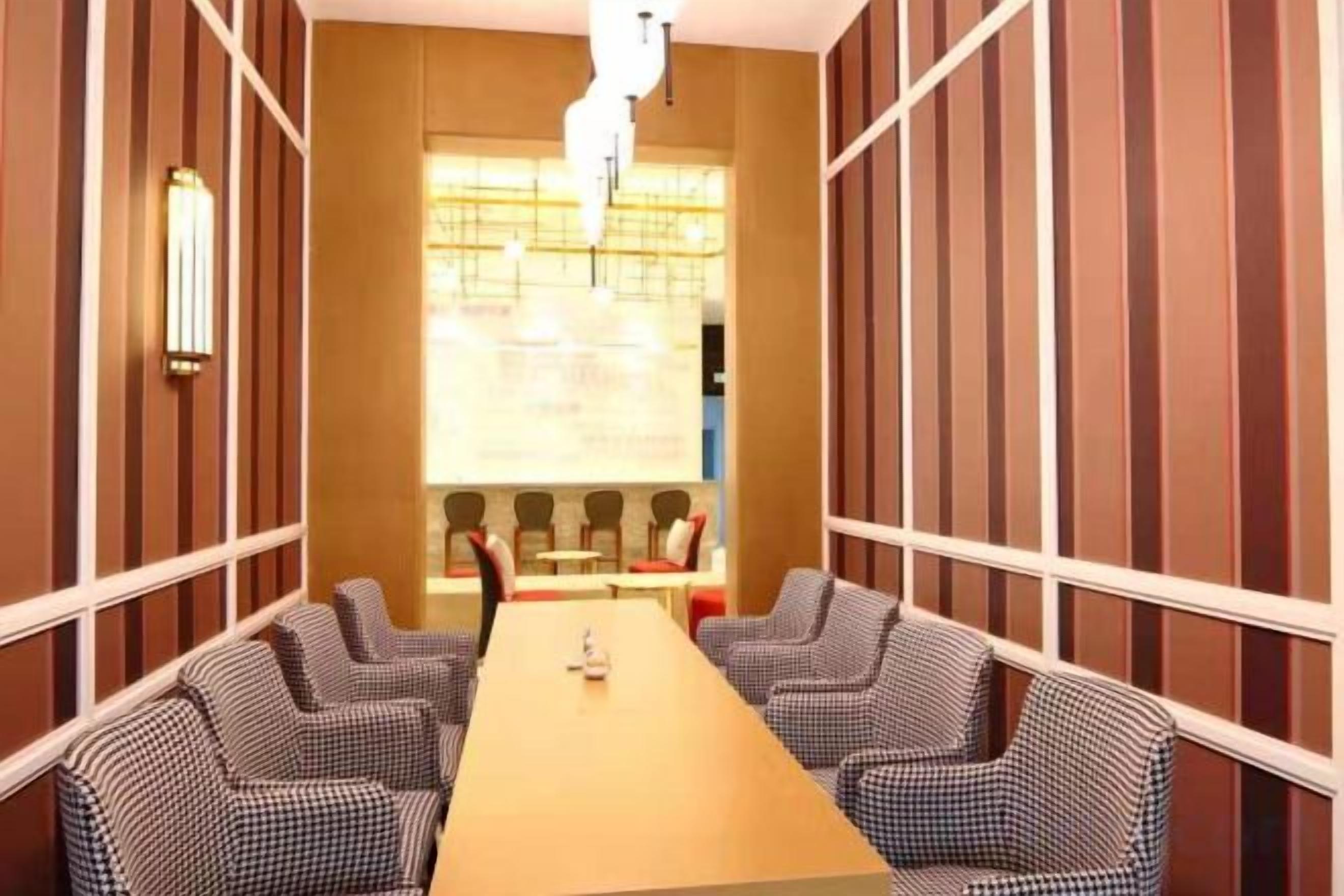 A conference room with a long table and four chairs, a large window with blinds, and a wall-mounted light fixture.