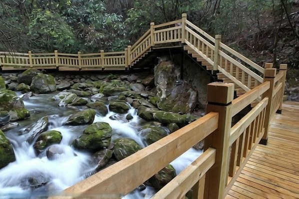 A wooden bridge over a flowing river with rocks, surrounded by greenery. - Magnotel Hotel (Nanjing Lishui Development Zone Baota North Road) (Nanjing)