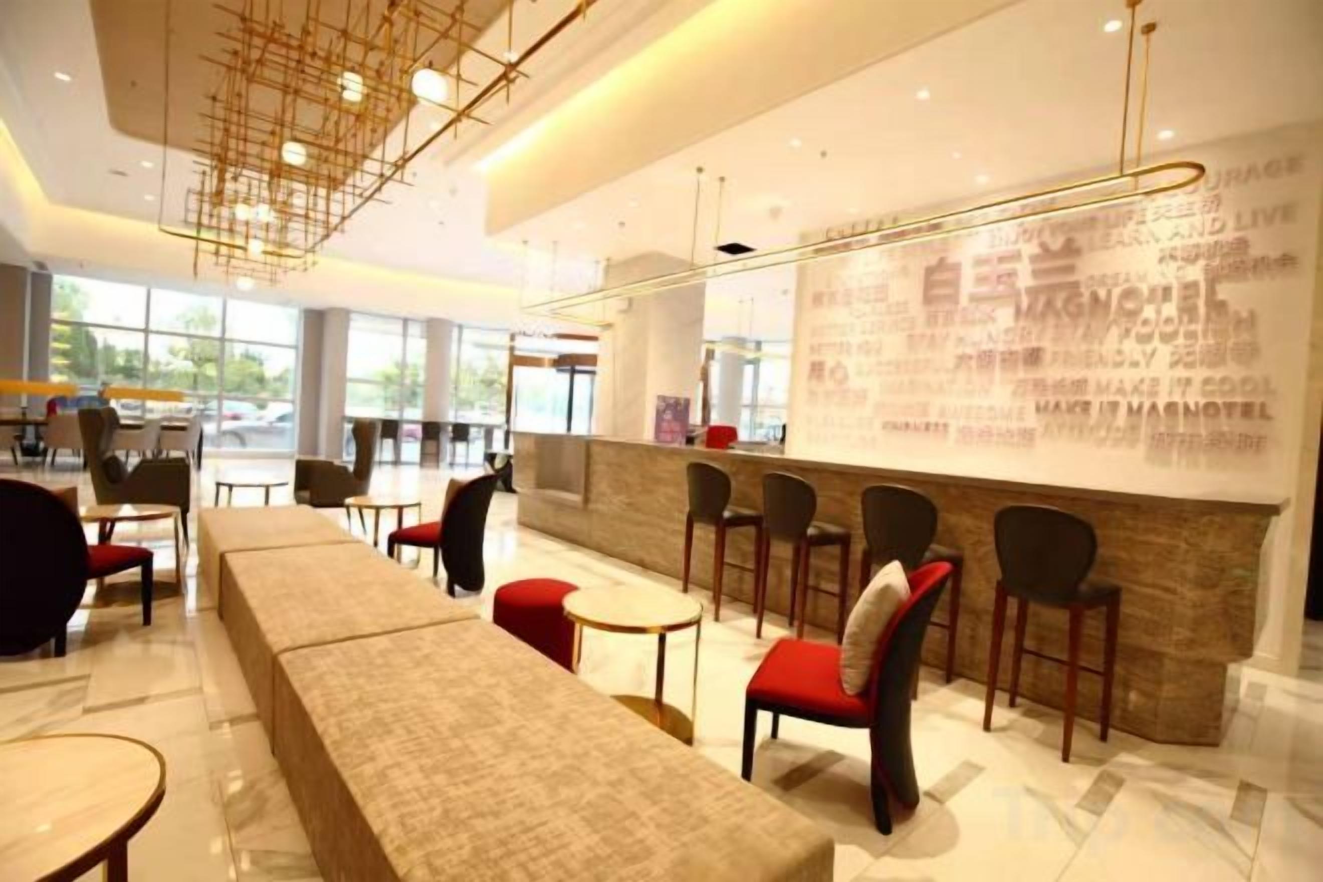 Un interior moderno con un largo banco, varias sillas, una zona de bar y grandes ventanales.