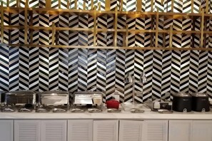 A buffet setup with various food containers and a patterned wall in the background. - Magnotel Hotel (Nanjing Lishui Development Zone Baota North Road) (Nanjing)