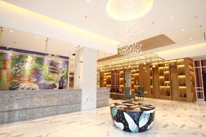 A hotel lobby with a reception desk, a seating area, and a decorative wall. - Magnotel Hotel (Nanjing Lishui Development Zone Baota North Road) (Nanjing)