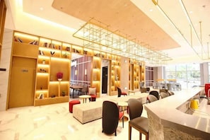 Un moderno vestíbulo de hotel con mostrador de recepción, zona de estar y una gran estantería.