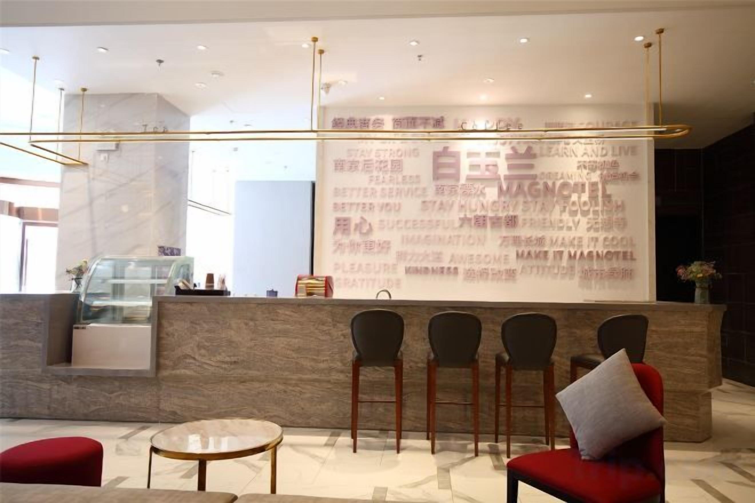 A reception area with a marble counter, four chairs, a red sofa, and a glass coffee table.