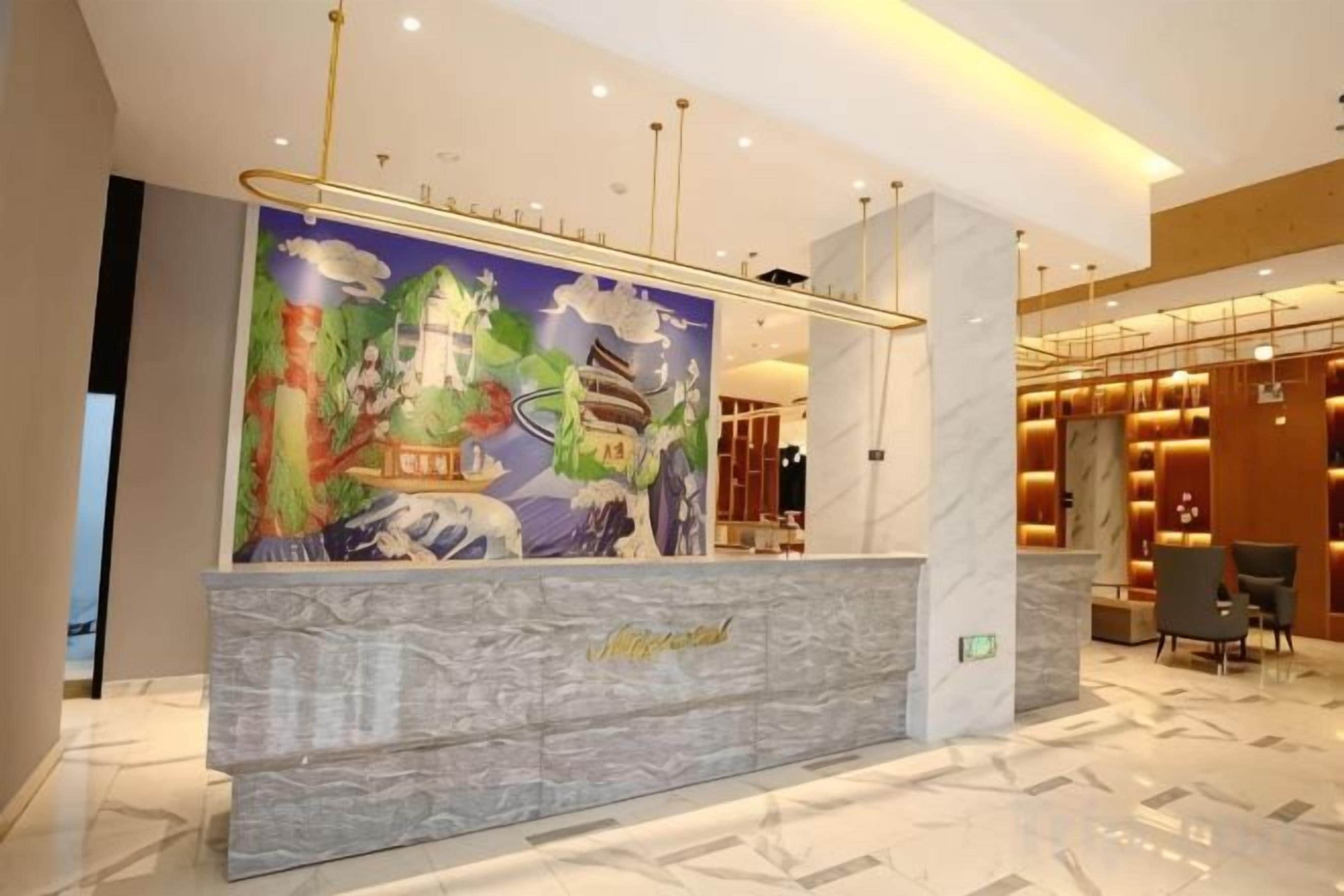 Una zona de recepción de hotel con mostrador de mármol, un mural y un diseño interior moderno.