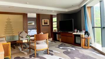 A hotel room with a bed, a desk with a computer, a television, and a large window.