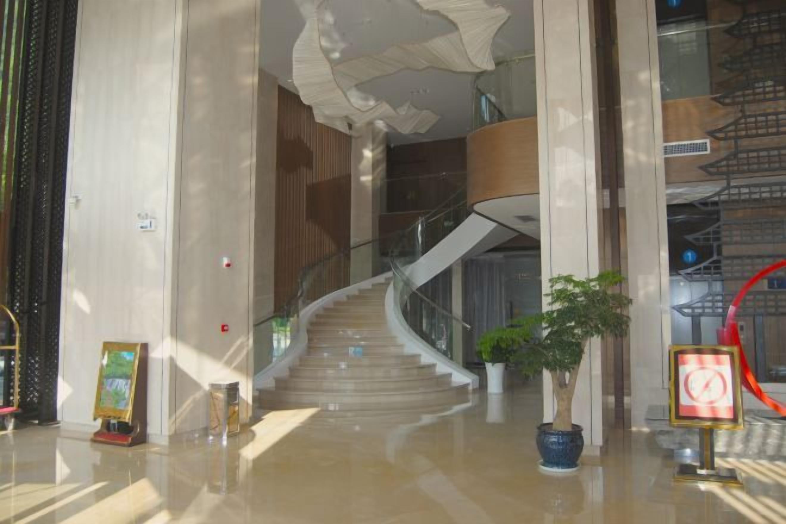 Un intérieur moderne avec un escalier à volutes, une plante en pot et un panneau avec un bord rouge.