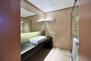 Uma casa de banho moderna com um espelho grande, lavatório e cabine de duche em vidro.