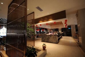 A hotel lobby with a reception desk, seating area, and decorative plants. - Xenp Xangh Xedt Lail Hotel (Congjiang)