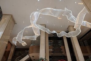 Ein modernes Interieur mit einer außergewöhnlichen Lichtinstallation, einer Treppe und einem traditionellen architektonischen Detail.