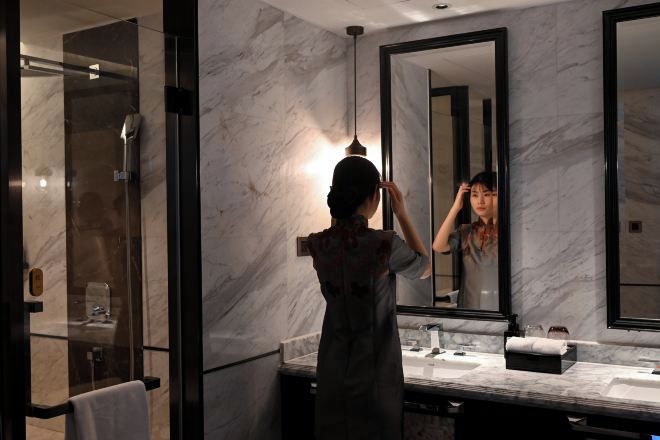 A modern bathroom with a large mirror, marble walls, and a glass shower enclosure.
