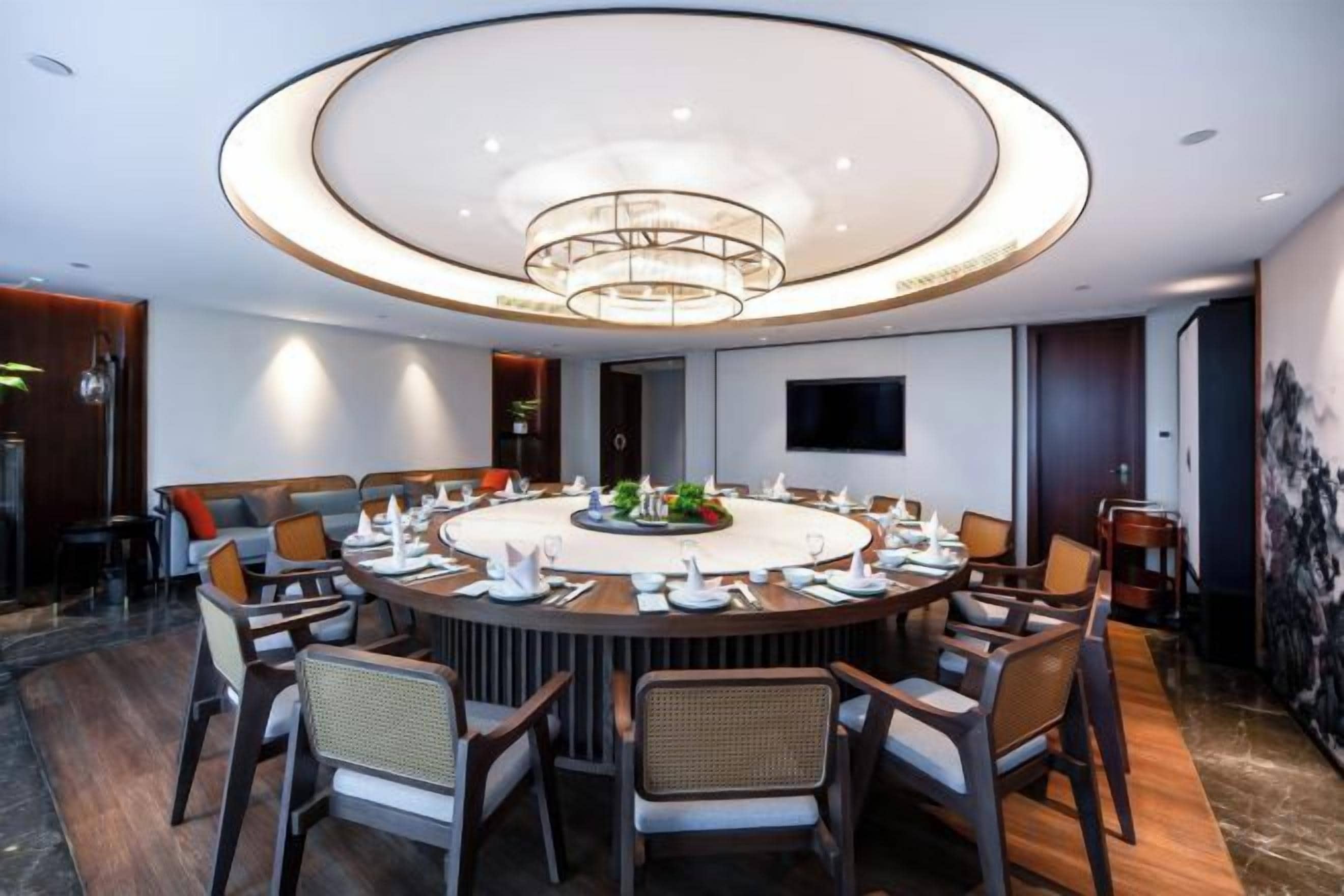 A modern dining area with a round table, chairs, and a central light fixture.