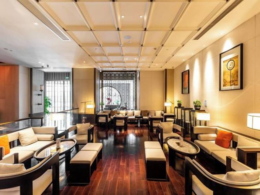 A spacious lobby with multiple seating areas, a large window, and a decorative wall.