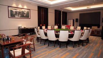 A hotel dining area with a round table, chairs, and a television screen.