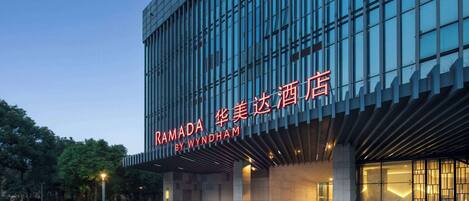 Ein modernes Gebäude mit einer großen Glasfassade und einem Schild mit der Aufschrift "RAMADA BY WYNDHAM".