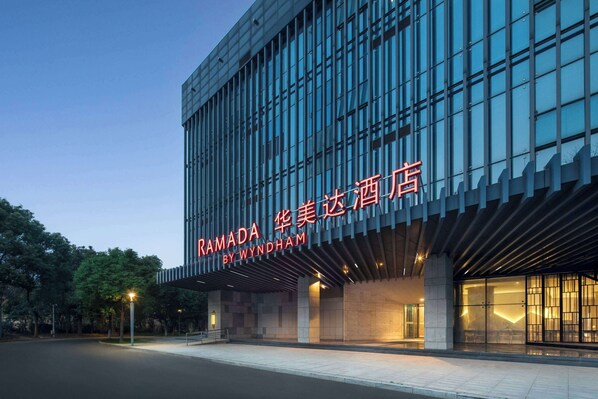 A modern building with a large glass facade and a sign reading "RAMADA BY WYNDHAM". - Ramada by Wyndham Zhenjiang Dagang New District (Zhenjiang)