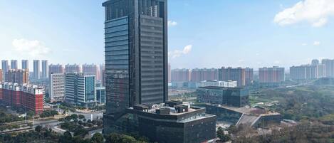 A high-rise building with a modern glass facade, surrounded by other high-rise buildings and greenery.