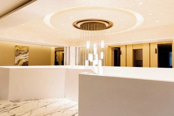 A modern hotel lobby with a marble floor, a central chandelier, and a reception desk. - Jiasheng Jinling Hotel (Nanjing)