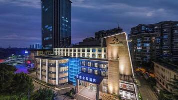 Un hotel moderno con fachada de vidrio destacada, un atrio central y una terraza en la azotea.