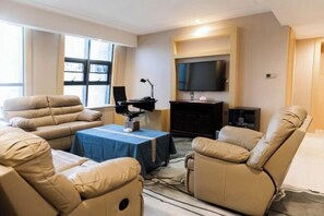 A living room with a sofa, two recliners, a coffee table, a TV, and a fireplace. - Jiasheng Jinling Hotel (Nanjing)