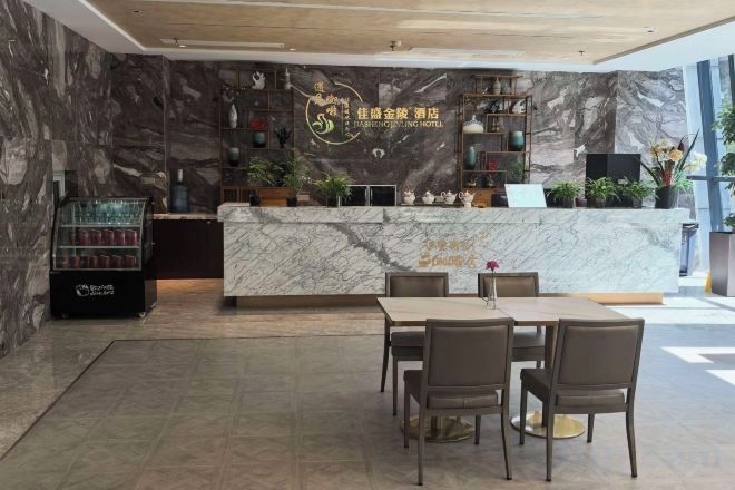 A hotel reception area with a marble counter, seating, and a display case.